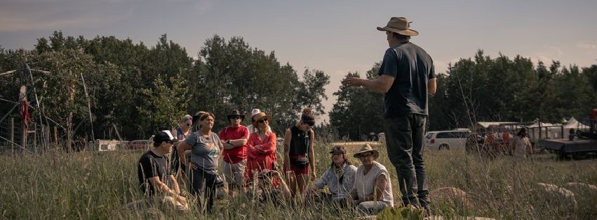 A photo of attendees of the Ness Creek Music Festival  participating in a guided forest walk, listening to someone speak.