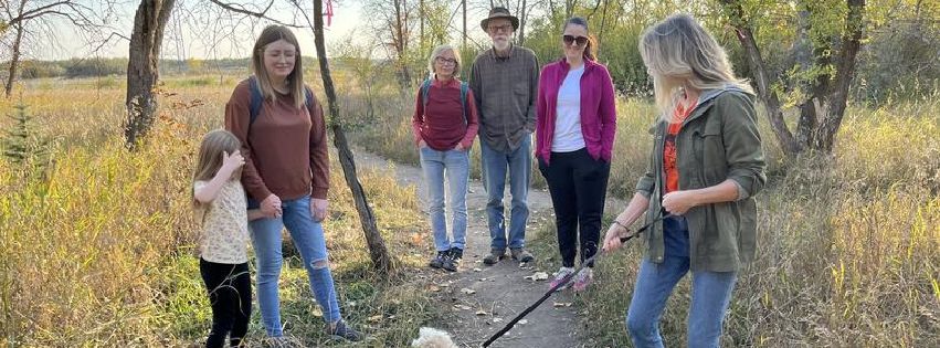 A photo of a small group of people and a dog visiting the Saskatoon Afforestation areas.