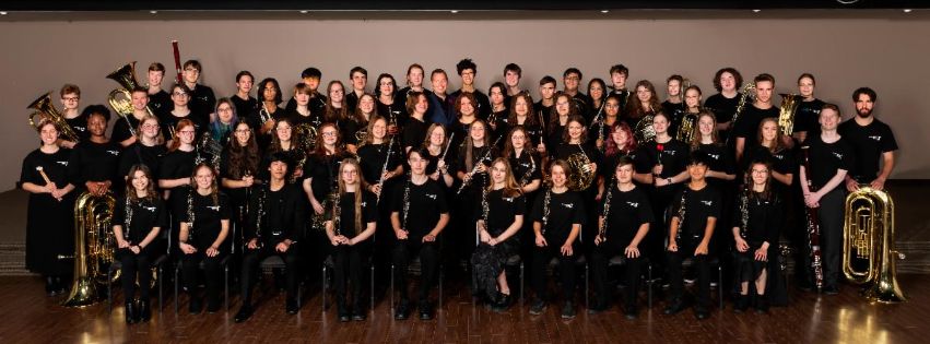 A group photo of kids in a school band, posing with their instruments.