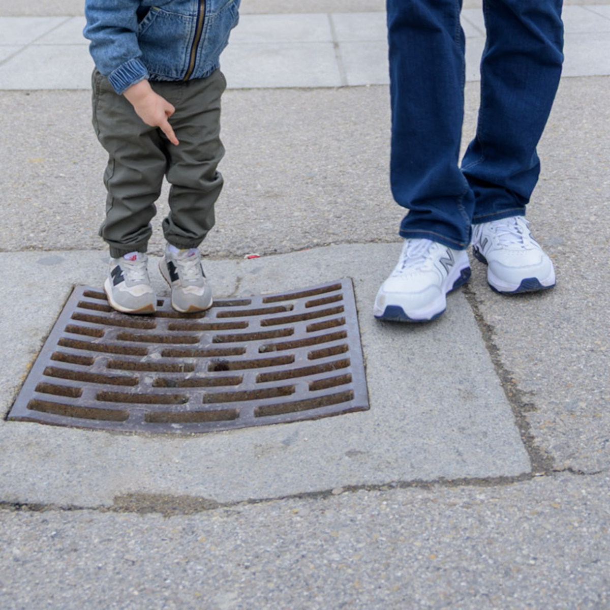 a boy and his dad inspecting an outdoor drain
