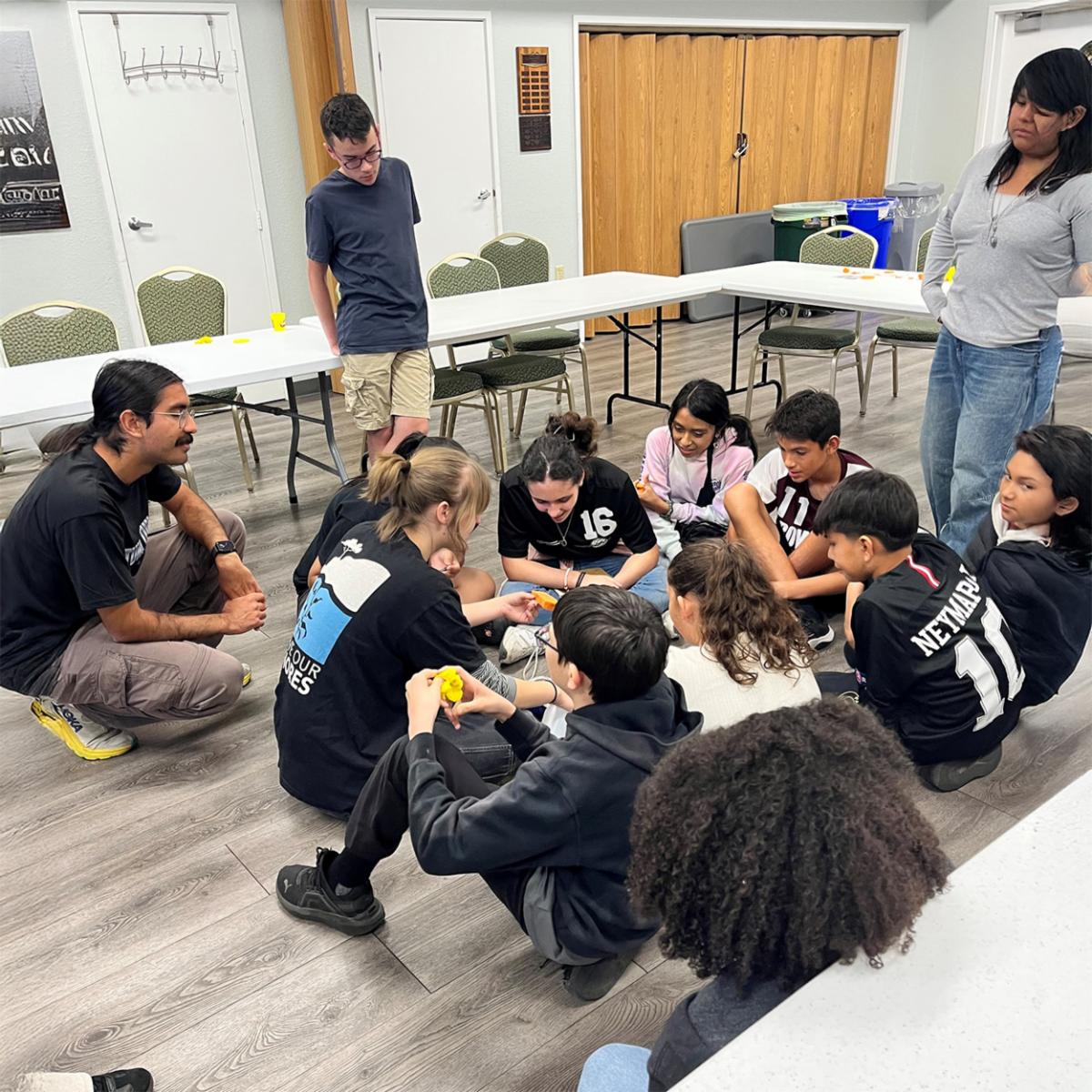 students gathered in a circle in a classroom studying an object