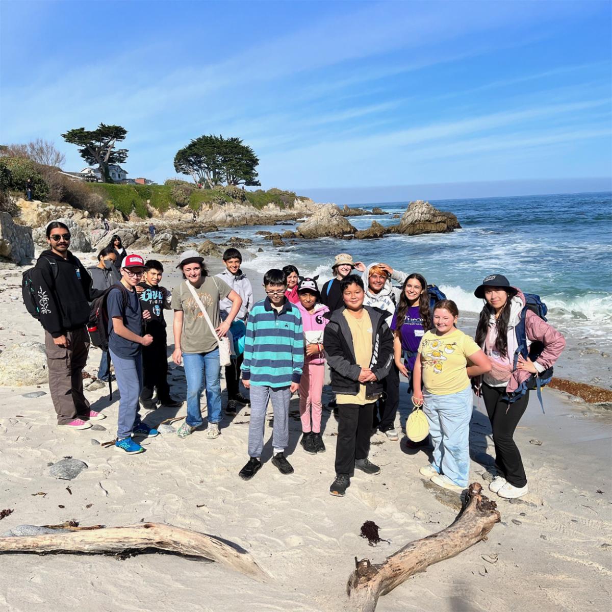 students gathered on a beach in front of the ocean