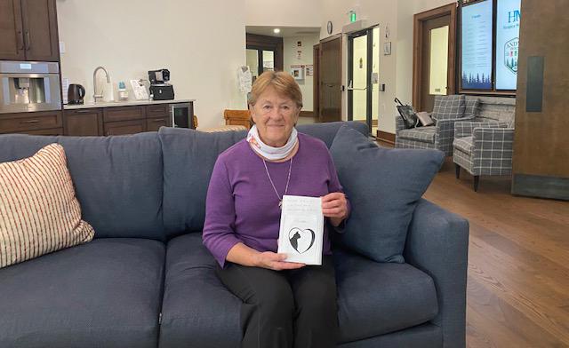 a woman holding a handmade book sitting on a sofa