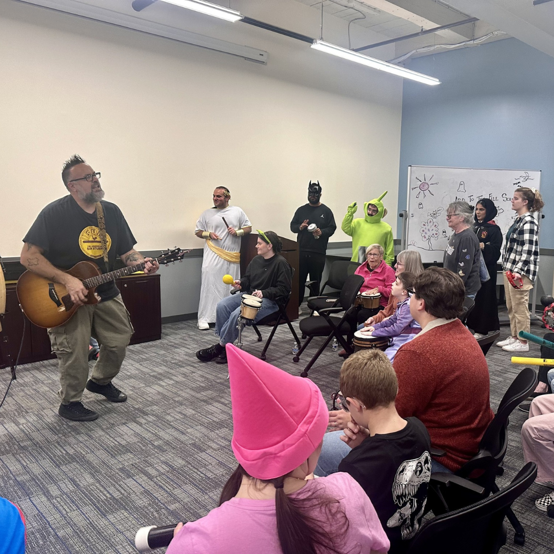 Musician Mike Leo strums his guitar as attendees of the Fall Social look on