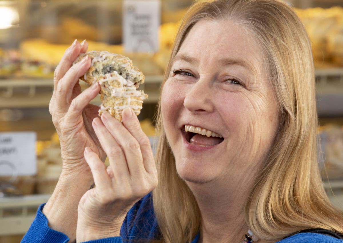 Rebecca Sharpless smiles as she holds up a piece of cornbread.