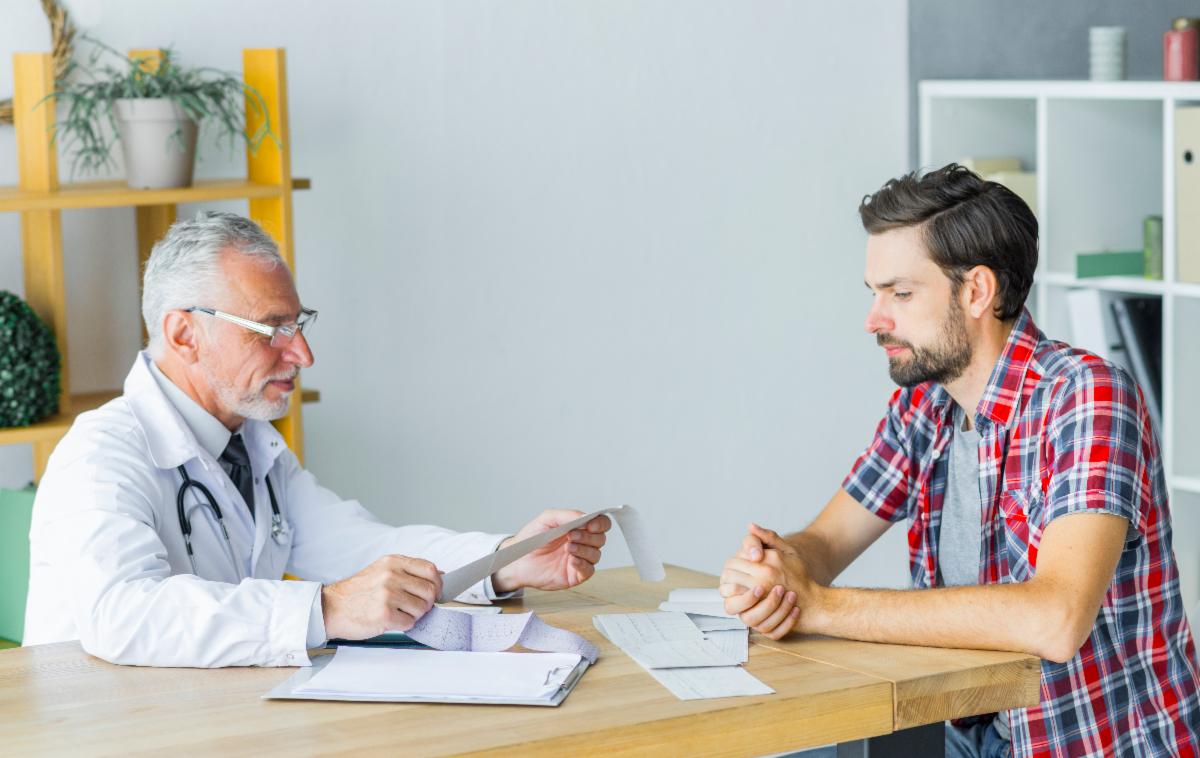 Healthcare provider discusses paperwork with a patient seated at a table.