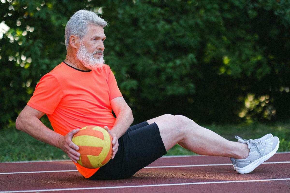 Person exercising on an outdoor track while holding a medicine ball.