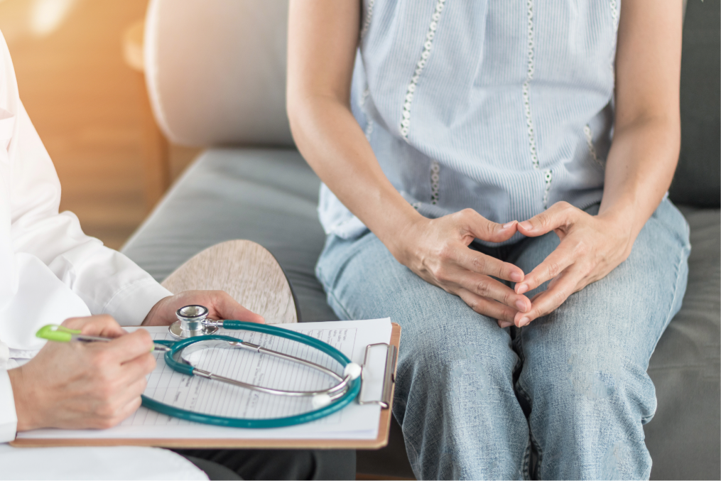Patient meeting with a healthcare professional during a medical consultation, with a stethoscope and clipboard visible in the foreground.