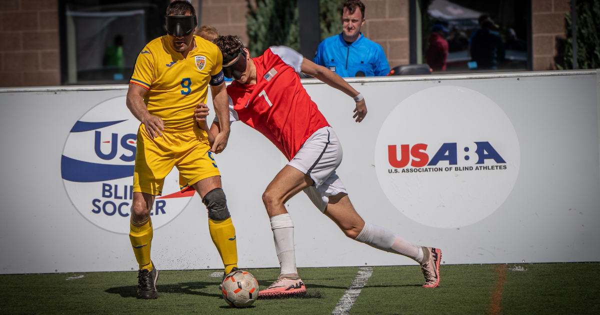 Blind Soccer athlete Ethan Kunes in Red challenging a romanian player in yellow for the ball 