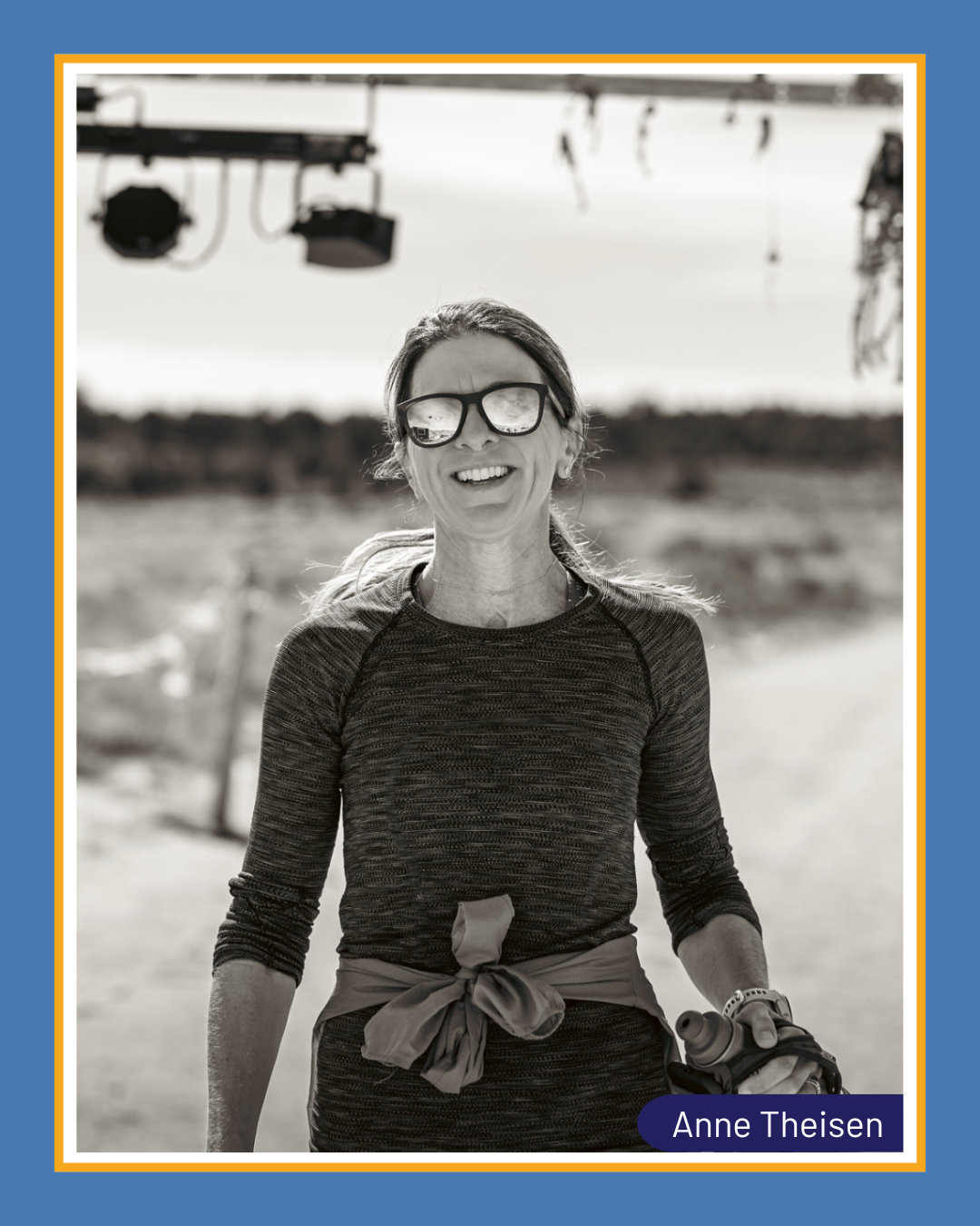 Team CureSHANK runner Anne Theisen smiling in sunglasses and workout clothes with a road and trees in the background.