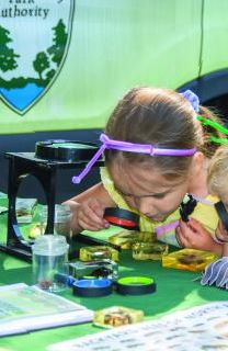 A child looks through a magnifying tool during an outdoor environmental education activity.
