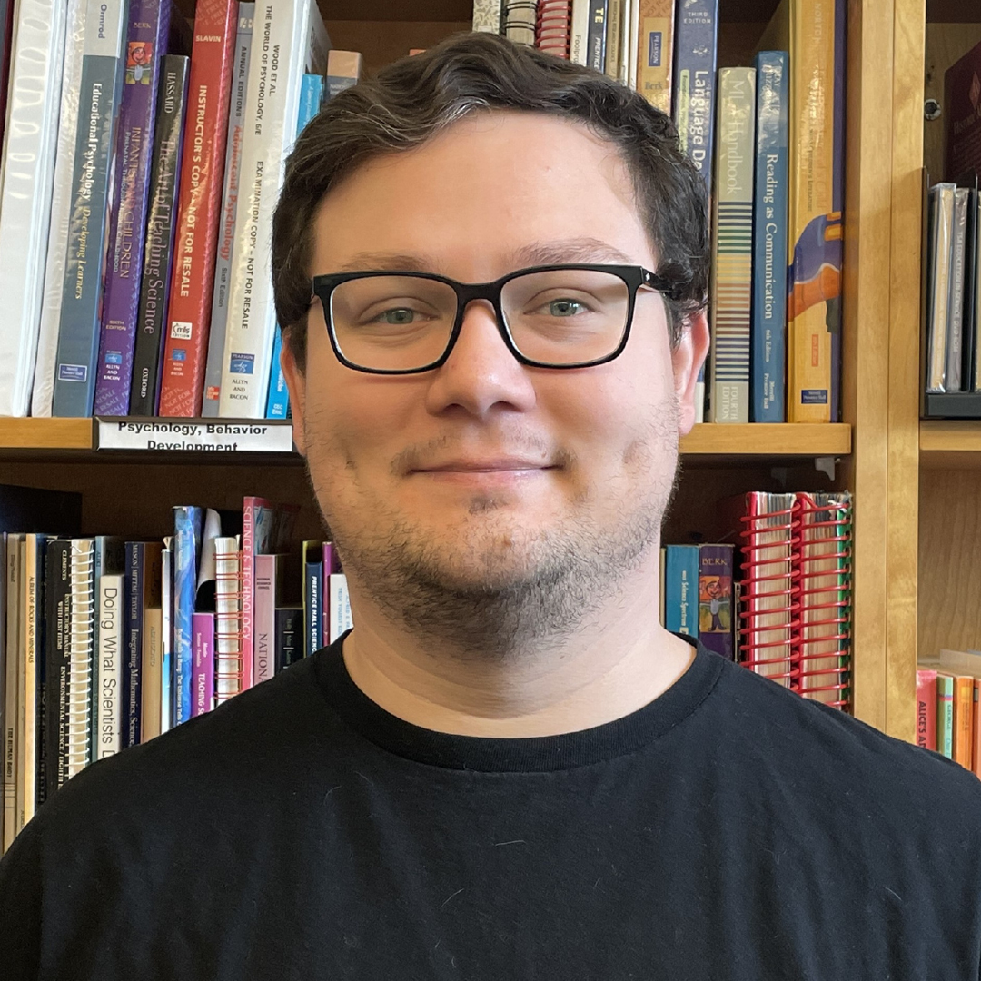 Andrew Costa smiling with book stacks in background