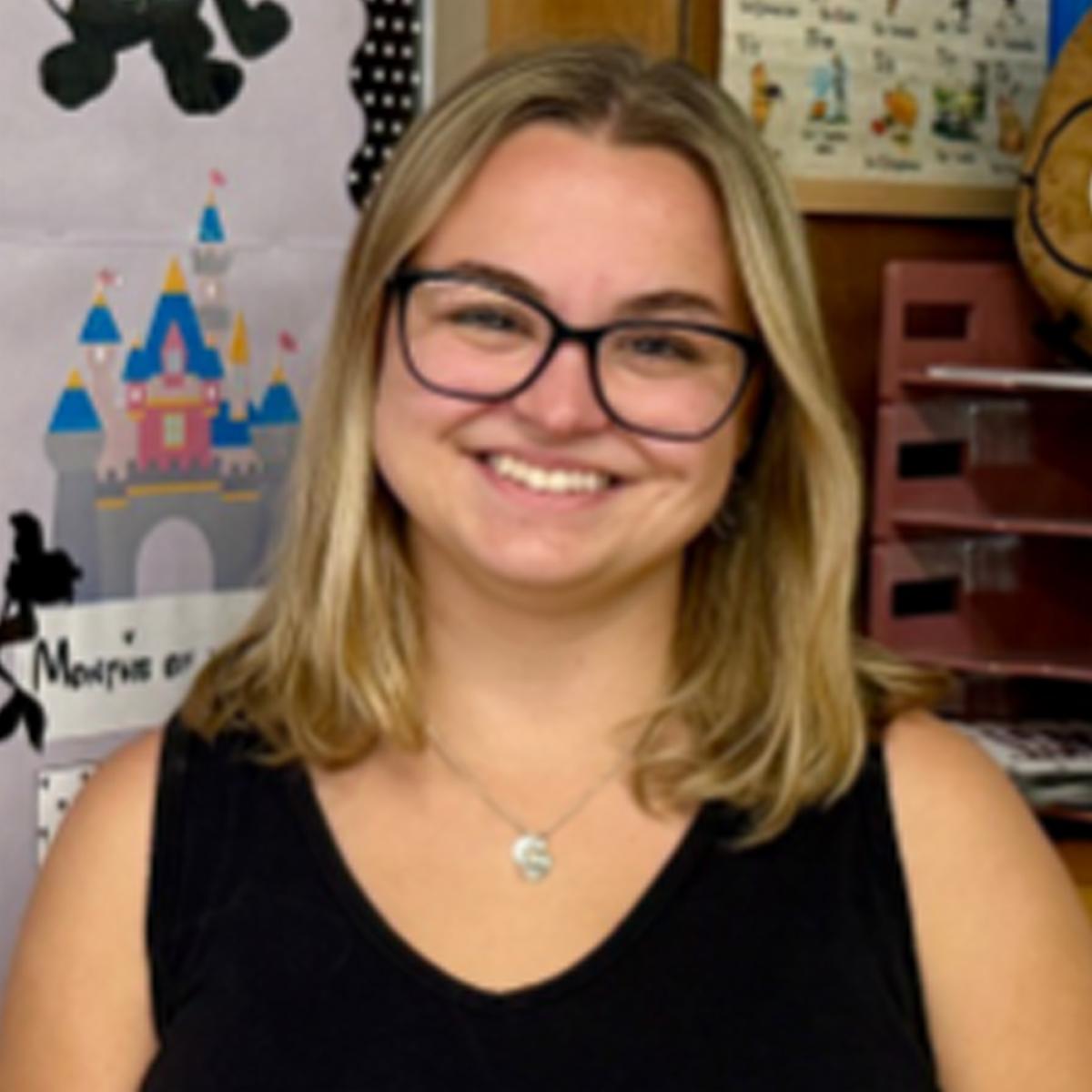 Erin smiling wearing black rimmed glasses and black shirt
