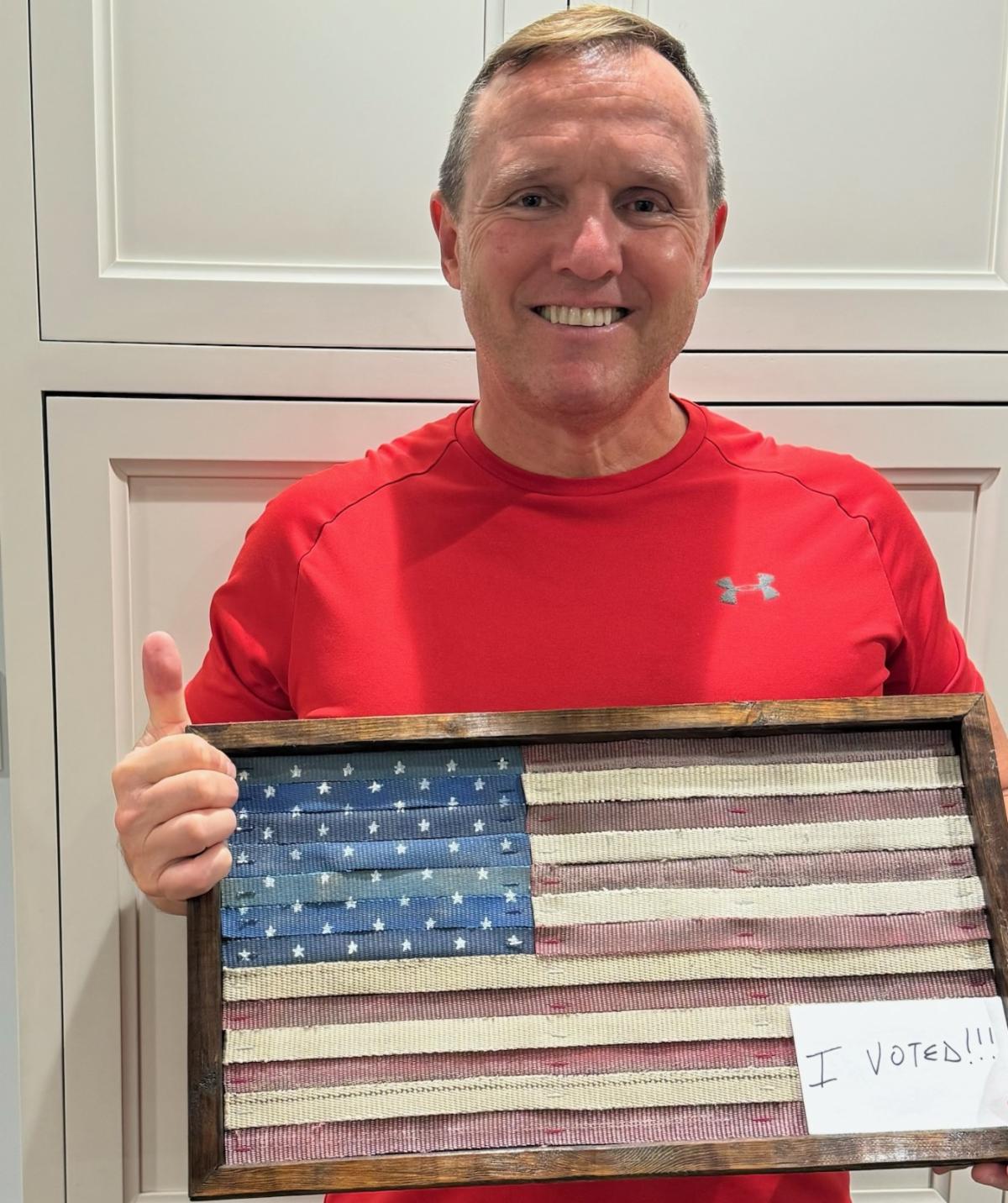 Ken holding American Flag artwork and I voted sticker