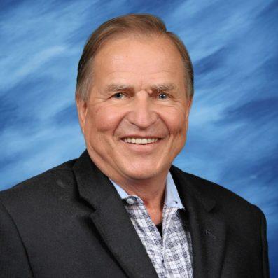 James smiling wearing suit jacket and plaid shirt