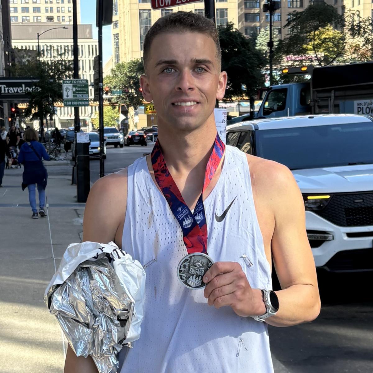 Kyle smiling holding medal from Chicago Marathon