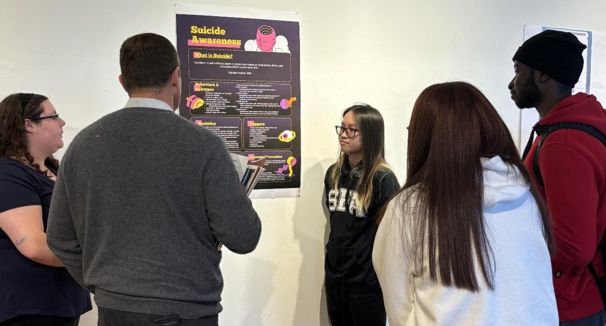 poster presentation with students and staff gathered in gallery