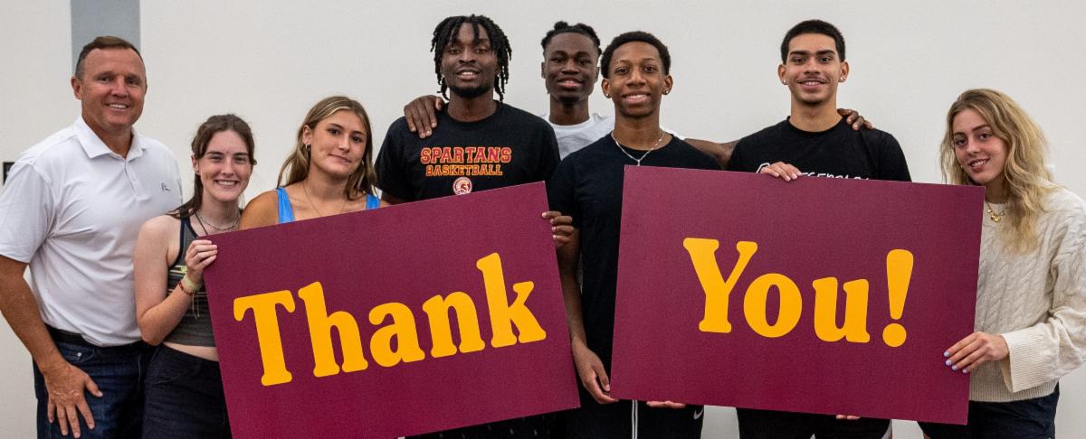 seven students holding up thank you sign with president daly