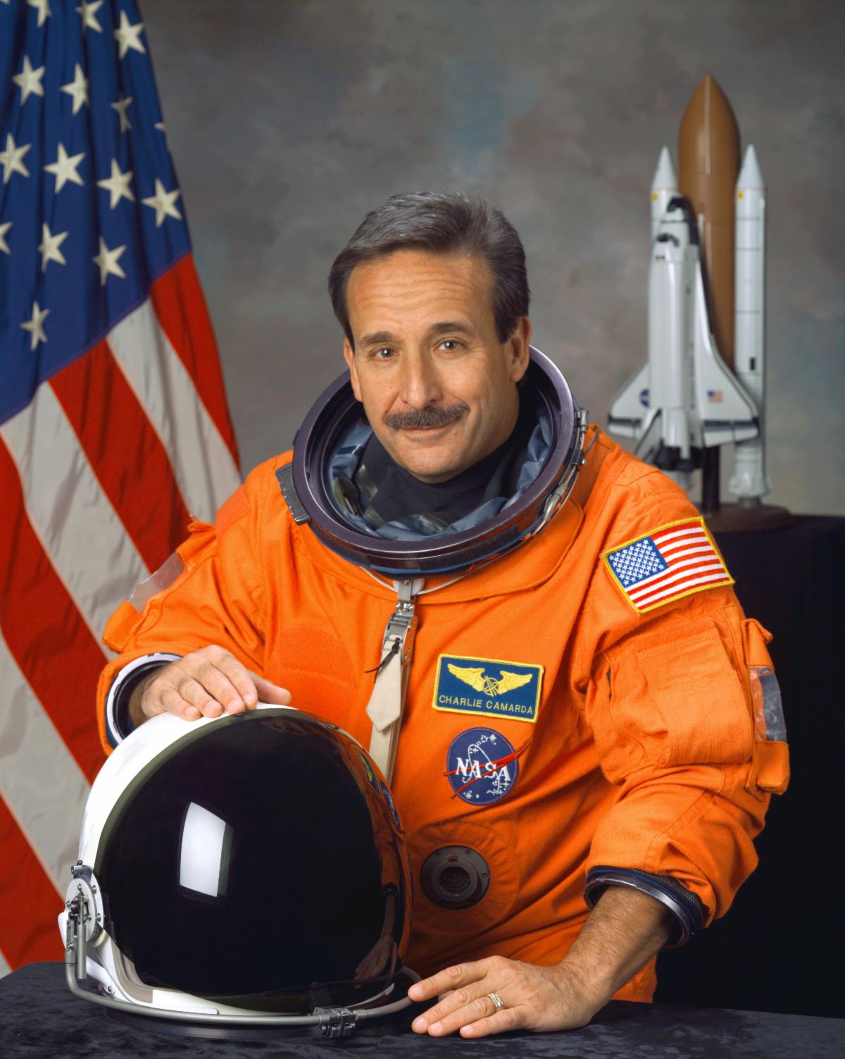 Charles Camarda headshot image smiling while wearing spacesuit and holding helmet