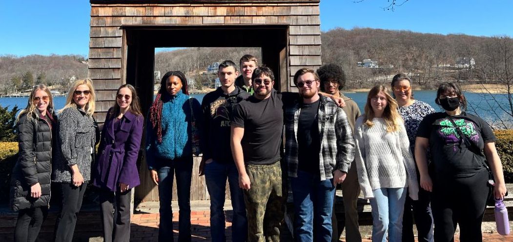 Group of students and administratiors smiling outside with River in background