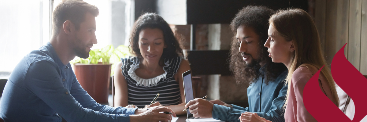 four students seated at table working on group project