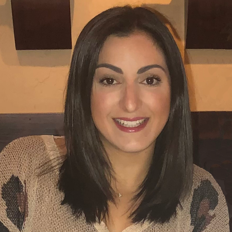 Jennifer smiling wearing brown sweater and shoulder length black hair