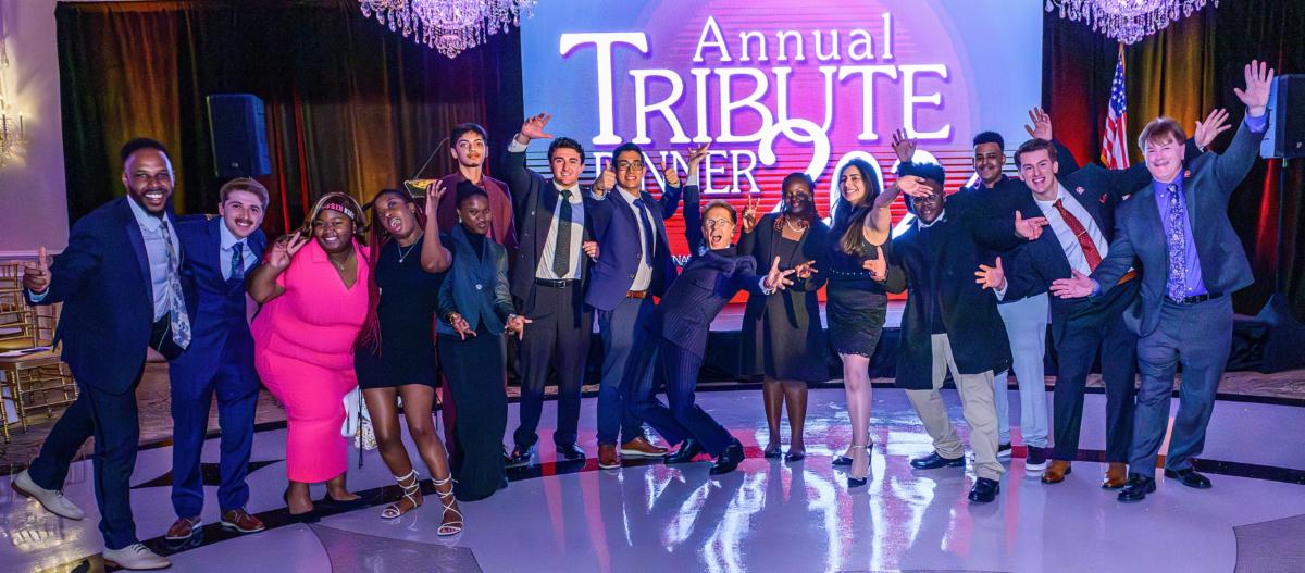 Tribute Dinner event with students and guests smiling for photo with hands up in air