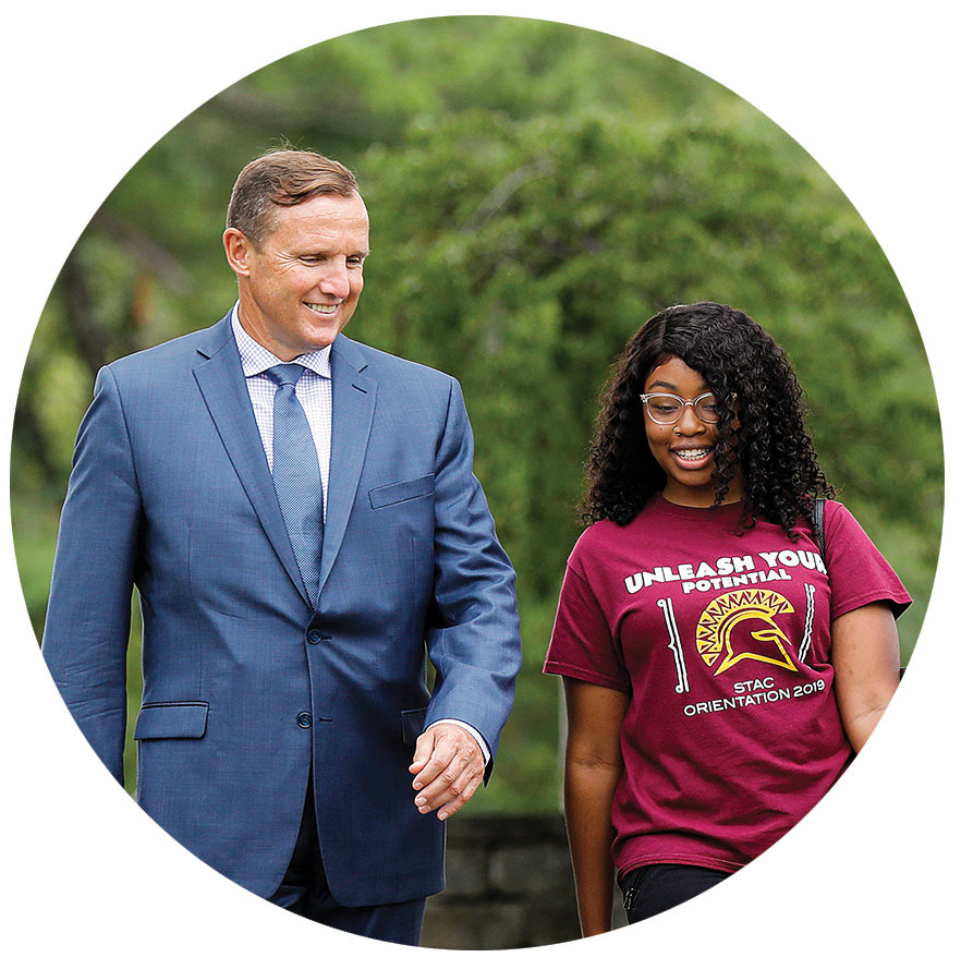 Ken walking with student outside chatting and smiling
