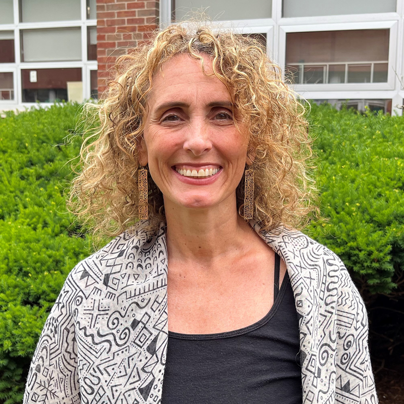 Stacy smiling outside with green bush in background