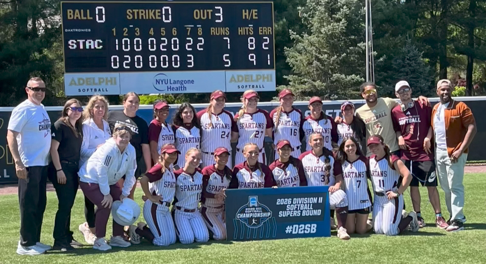 softball team posing with college administration smiling with super regionals banner
