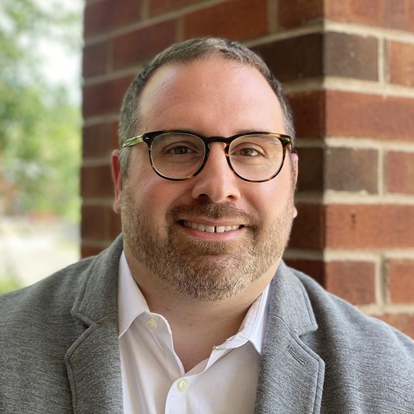 Mike smiling wearing glasses and gray blazer