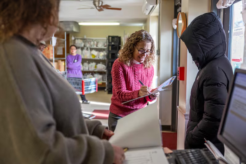 Photo of Pr. Tricia checking in a guest to get food.