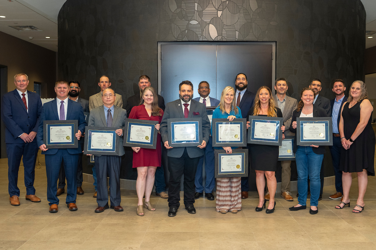 A row of people in business attire holding awards certificates