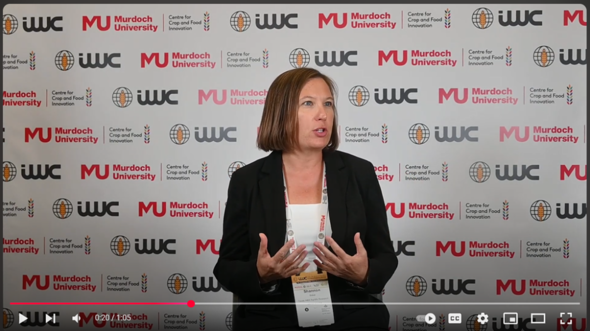 woman speaking in front of a step-and-repeat banner