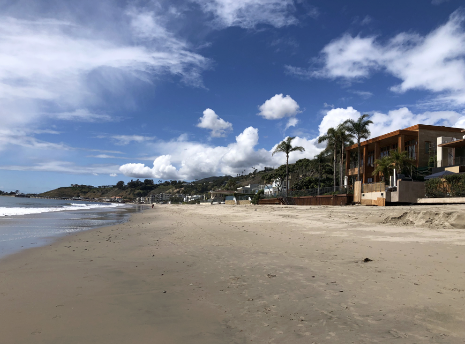 Carbon Beach shoreline in Malibu with oceanfront homes and the Malibu Pier in the distance.
