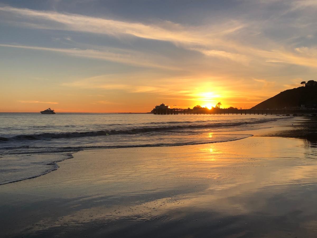 Sunset over Carbon Beach Malibu with calm waves and golden sky.
