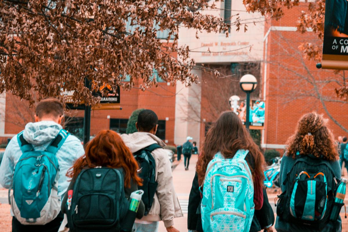 High school students with backpacks heading into a school building