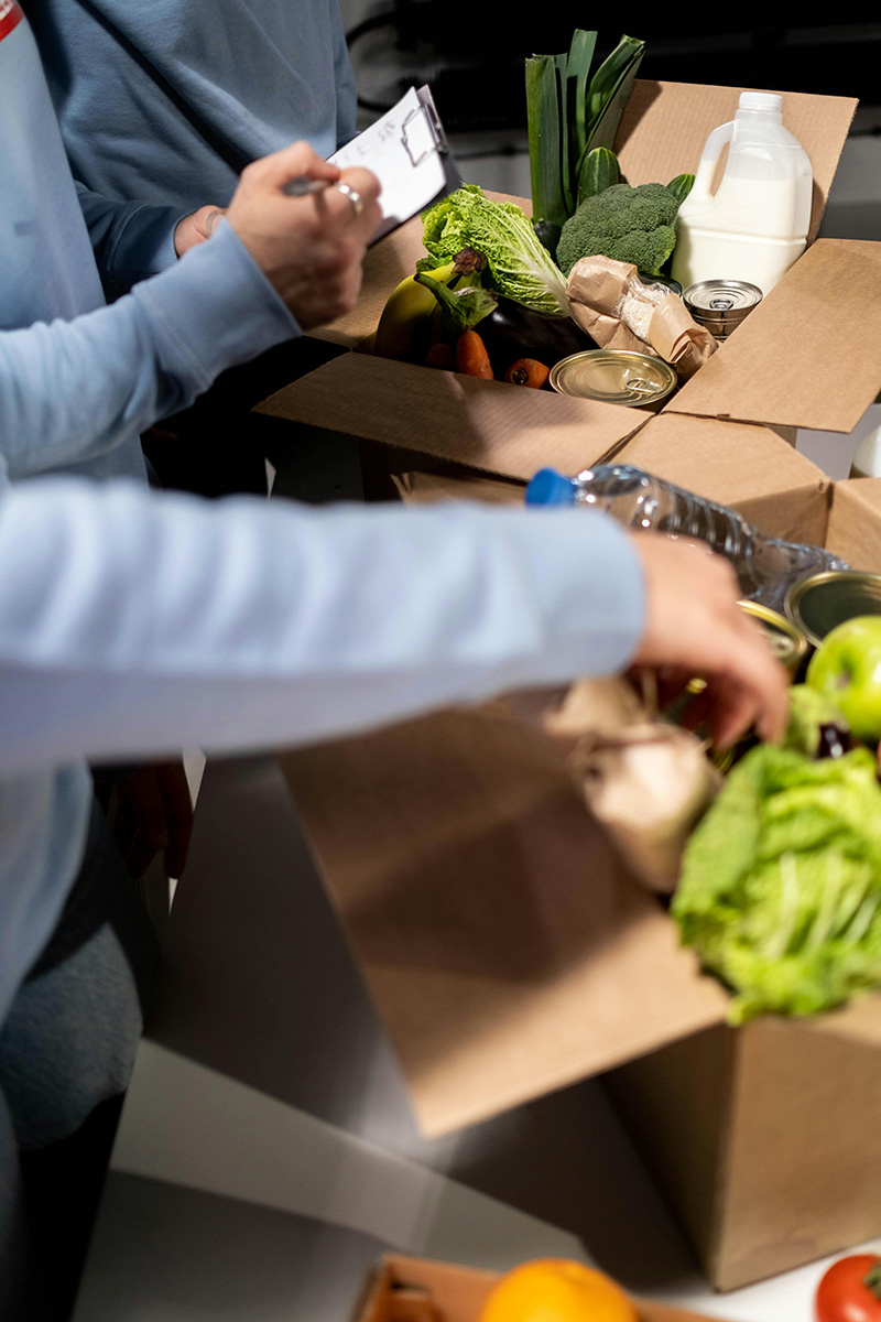 People's hands putting food into food donations boxes