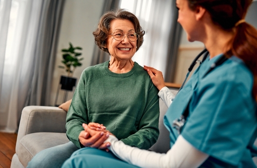 General practitioner talking to a senior woman during home visit.An elderly woman smiles and receives emotional support and help.