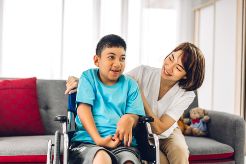 Portrait of enjoy happy love family asian mother playing and carer helping look at disabled son child sitting in wheelchair moments good time at home.disability care concept