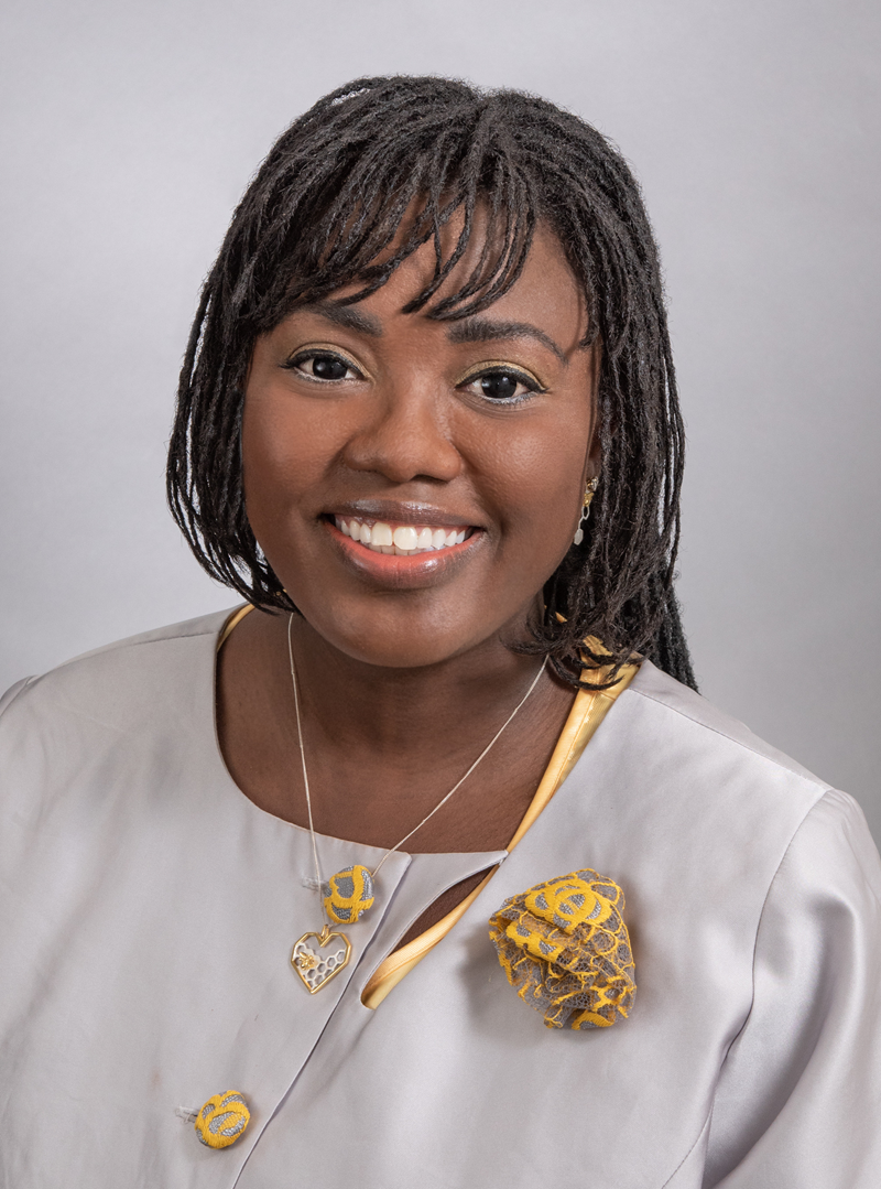 head shot of Candi Danielle wearing an ivory colored suit with gold trimmings and a beautiful smile