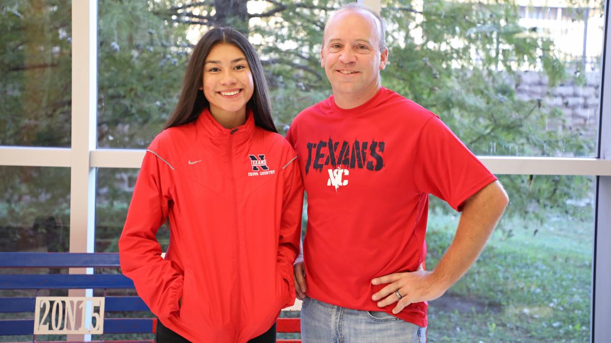 Kayla Martinez poses with coach Burke Binning at Northwest High School in XC attire