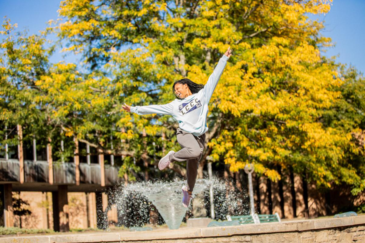 An LCCC student jumps in the air near the campus fountain