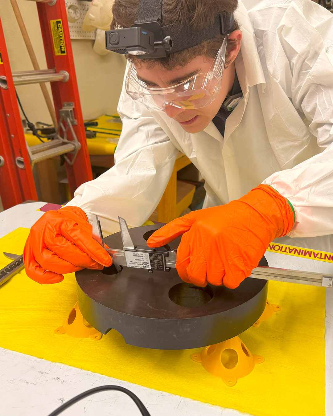 A student takes a measurement of a part from AGN-201