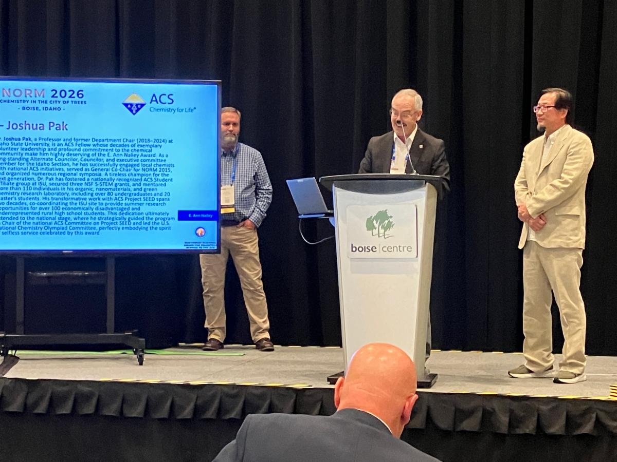 Josh Pak, professor of chemistry, stands on stage while receiving his E. Ann Nalley Regional Award for Volunteer Service to the American Chemical Society in Boise, Idaho.