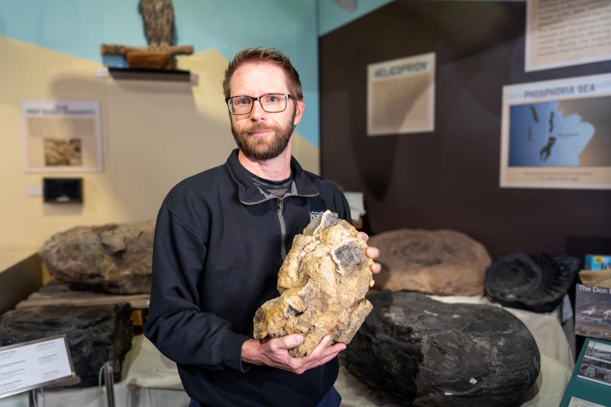 Leif Tapanila director of the Idaho Museum of Natural History and professor of geosciences at Idaho State University poses for a photo holding a piece of chert containing spicules