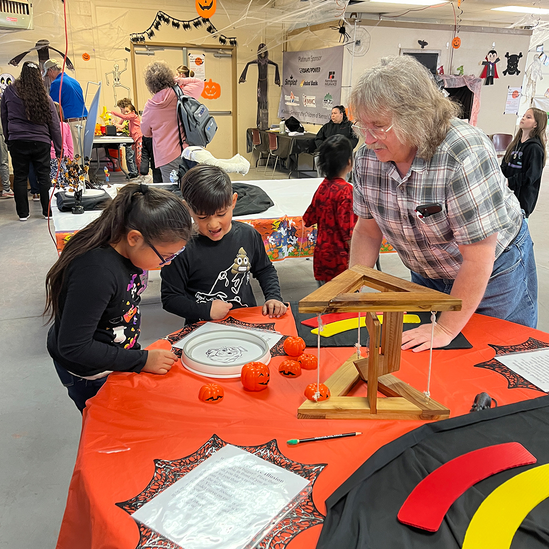 Steve Shropshire professor of physics and lead organizer of the Haunted Science Laboratory assists students with an activity during a 2024 field trip to the Haunted Lab