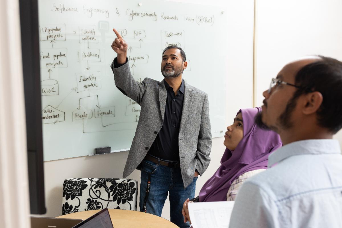 Minhaz Zibran professor Arifa Islam Champa and Md Fazle Rabbi look over code at Idaho State Universityâs Department of Computer Science.