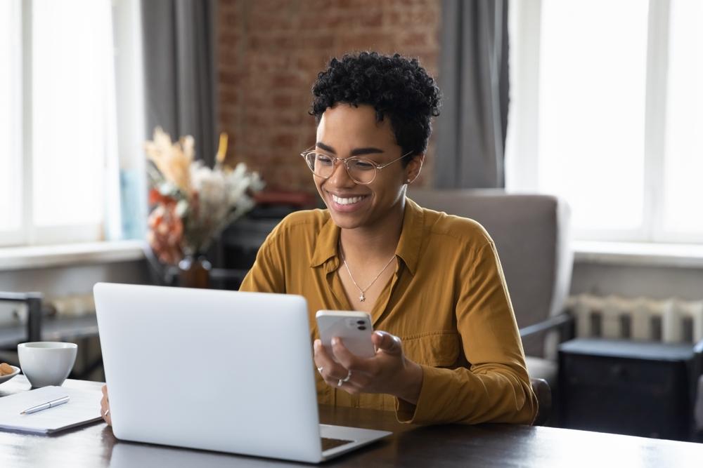 A business owner at her desk smiles while working on her laptop computer.