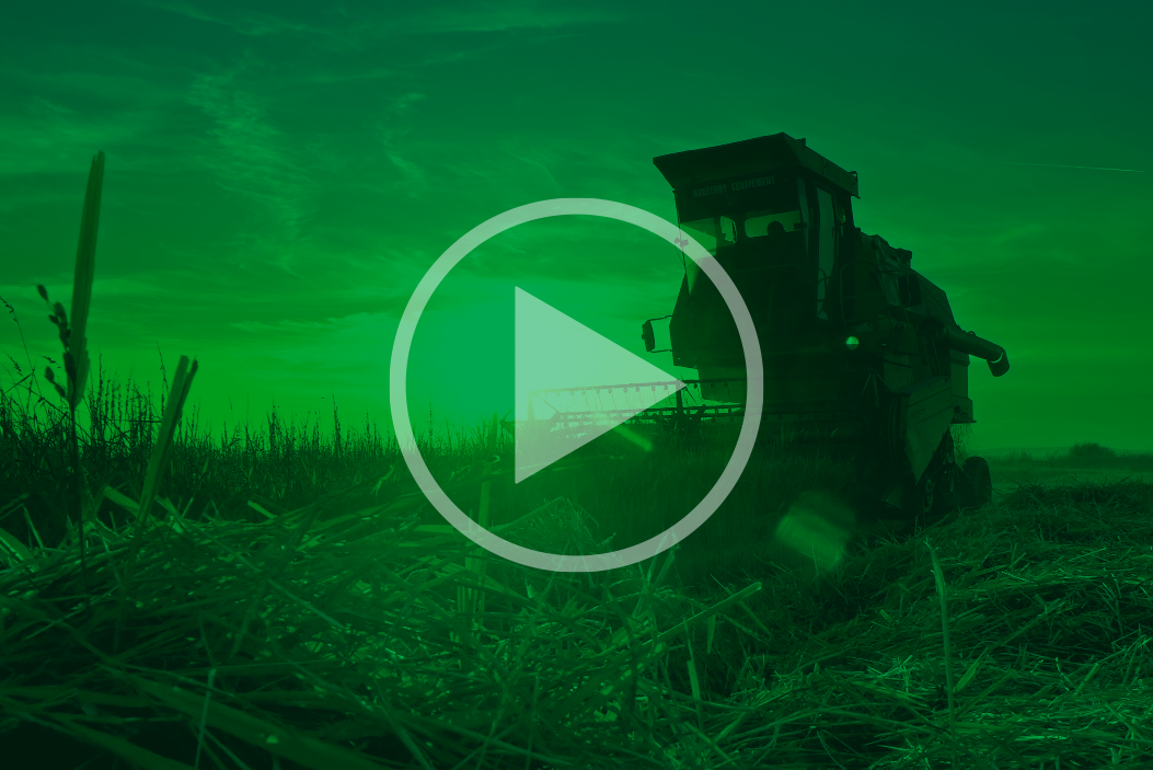 Image of a combine harvester in a field with a video play icon overlayed.